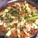 spanish paella mexican style, topped with acodaco, coriander leaf and lime