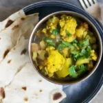 aloo gobi - cauliflower and potato curry in a dish with naan bread