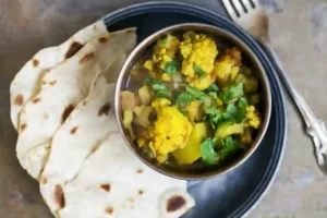 aloo gobi - cauliflower and potato curry in a dish with naan bread