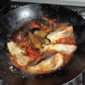 metal pot (Kadhai) with aubergines and curry sauce in the preparation of dopiaza