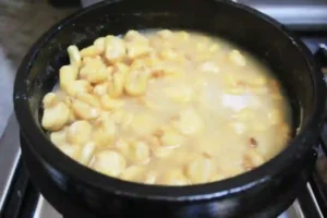 white corn being being nixtamalized in a lime wash solution in a black clay pot