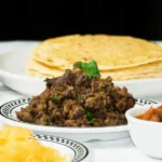 refried black beans recipe: served on a white dish with yellow corn tortillas