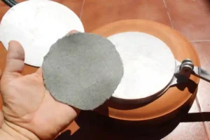 Manuel holding a fully formed blue corn tortilla, ready to transfer to from press to skillet