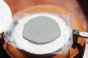 a blue corn tortilla on a press, ready for cooking on the comal / skillet