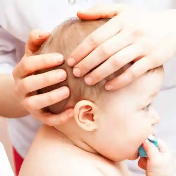 practitioner using cranial osteopathy on a seated baby's head