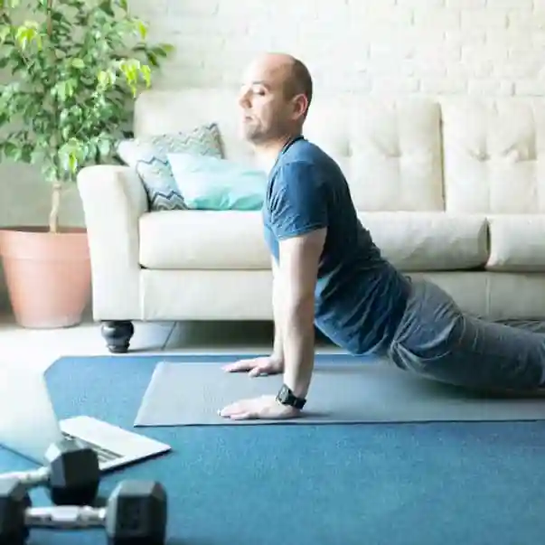 man with laptop in yoga cobra pose on a live online class