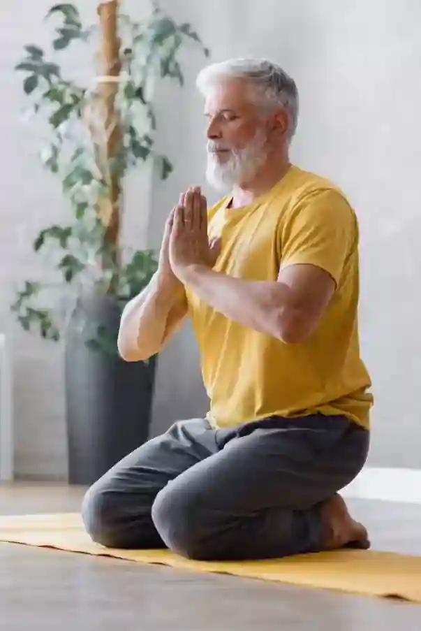 Older man with sliver hair and beard, seated eyes closed in meditation on a therapeutic yoga session